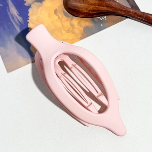 Détail d'une grande pince à cheveux rose mat sur un fond texturé élégant