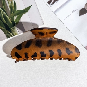 Detail of a large amber leopard print hair claw clip on a stylish textured background