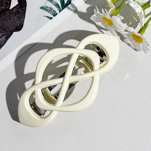 Detail showing the cream geometric knotted hair clip with a matte finish spring base
