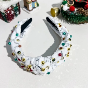 Detailaufnahme vom Weihnachts-Haarreif mit bunten Perlen und Pailletten auf weißem Plüsch