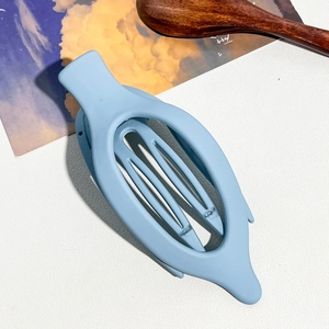 Gros plan sur la pince à cheveux banane bleu clair mate avec design ovale évidé et courbé