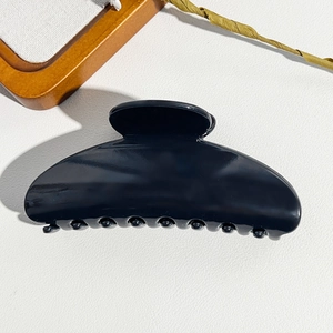 Close-up of a large black semi-circular hair claw clip with a glossy polished finish