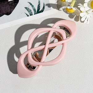Close-up of pink geometric ABS hair clip with crossed weave design and spring clasp