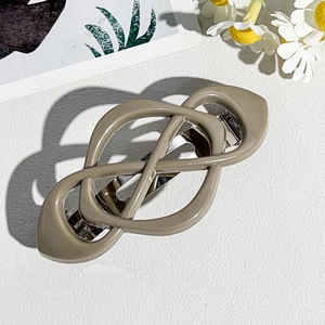 Detail of a milky brown geometric spring hair clip on a textured white background
