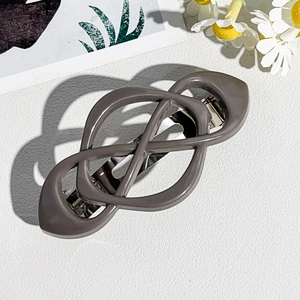 Macro view of a dark grey infinity knot hair clip with a silver metal spring fastener