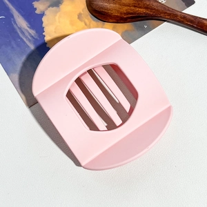 Vue rapprochée du coupe-œuf rose avec fils en acier inoxydable sur fond blanc texturé
