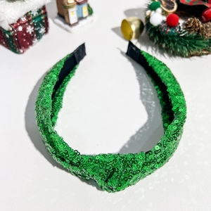 Detailansicht eines verknoteten grünen Pailletten-Haarreifs mit festlicher Weihnachtsdeko