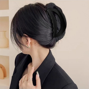 Large black crescent hair claw clip in matte finish shown on elegant updo hairstyle