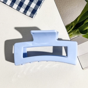 Vue détaillée de la pince à cheveux carrée évidée bleu clair de 8,5 cm sur fond texturé