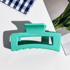 Détail de la pince à cheveux carrée de 8,5cm en silicone vert menthe sur fond texturé