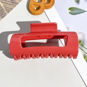 Close-up of soft silicone coral red shark hair claw clip on a minimalist white backdrop