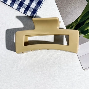 Vue détaillée d'une grande pince à cheveux mate rectangulaire sur fond cuir blanc cassé