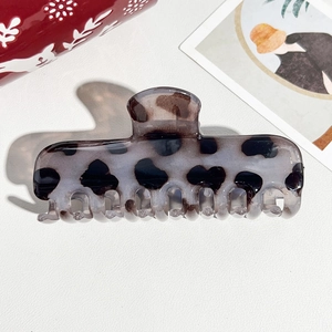 Close-up of a tortoiseshell acetate hair claw clip with dark spots on a white surface