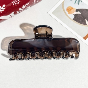 Macro shot of translucent brown hair claw clip with multi-tooth design on leather surface