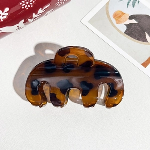 Detailed view of tortoiseshell resin hair claw clip with a glossy translucent finish