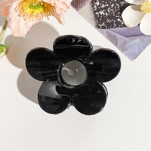 Dettaglio di un fermaglio a fiori nero lucido su uno sfondo decorativo elegante