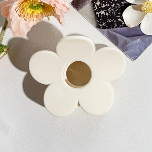 Dettaglio di un fermaglio per capelli a fiore bianco crema con centro cavo in resina
