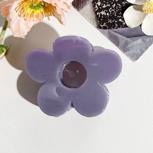 Dettaglio macro della molletta per capelli a fiore lilla con finitura lucida e design elegante