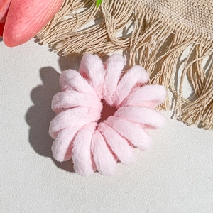 Gros plan sur l'élastique à cheveux spirale en peluche rose avec texture douce