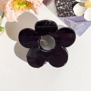 Macro della pinza per capelli a fiore nero con design a intaglio e finitura lucida