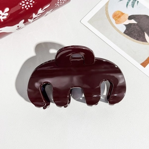 Macro detail of glossy dark red hair claw clip on elegant textured surface