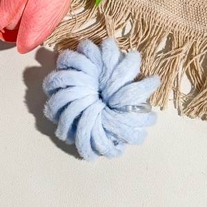 Détail d'un chouchou en peluche bleu clair avec design en spirale et texture douce