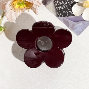 Dettaglio di un fermaglio per capelli a fiore rosso bordeaux con finitura lucida