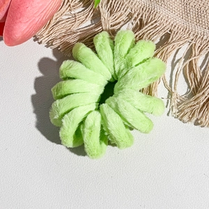Vue détaillée d'un chouchou en peluche vert clair à texture douce et forme spirale