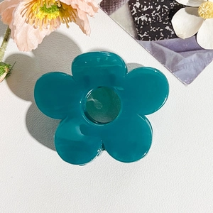 Dettaglio molletta capelli a fiore traforato blu su sfondo in pelle bianca