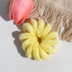 Gros plan d'un élastique à cheveux en peluche jaune clair en forme de tournesol doux