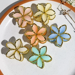 Detail of colorful floral hair claws with golden metal frames and resin flower petals