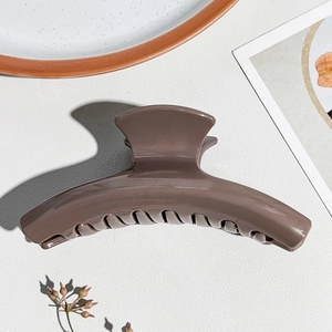 Dettaglio di una pinza per capelli in silicone marrone caffè su sfondo lussuoso
