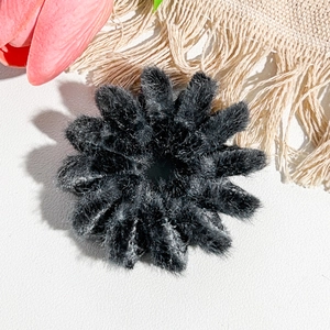 Gros plan sur une pince à cheveux nid d'oiseau noire floquée avec texture en peluche