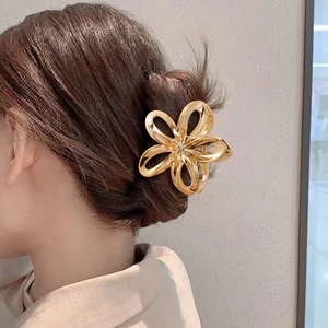 Detailed back view of a golden metal plumeria flower claw clip for elegant bun hairstyling