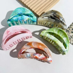 Detailed view of large marble texture hair claws in five colors with semicircular design