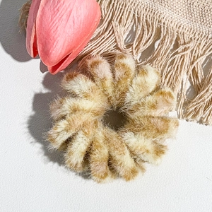 Gros plan d'un chouchou en peluche beige doux avec texture florale sur fond texturé