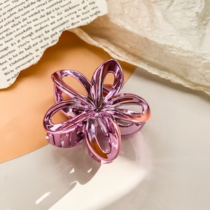 Detailed close-up of a pink-purple metallic frangipani hair claw clip on orange card