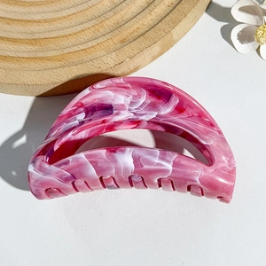 Detailed view of pink marble patterned acetate shark hair clip on wooden decor