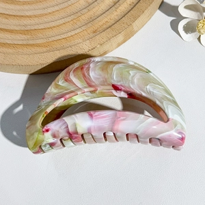 Macro shot of large crescent hair claw featuring pink and green marble texture finish