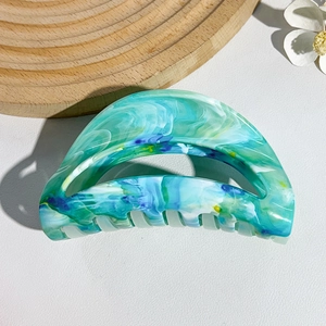 Detail of large semi-circular hair claw clip featuring mint green and white marble texture
