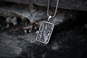 Macro detail of gothic stainless steel pendant featuring vintage relief carving on stone