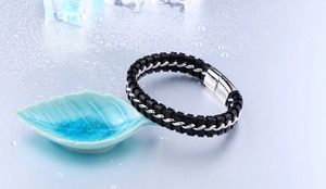 Gros plan du bracelet en cuir tressé noir avec fermoir magnétique en acier et gouttes d'eau