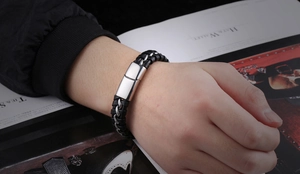 Gros plan d'un bracelet en cuir tressé noir pour homme avec chaîne argentée au poignet