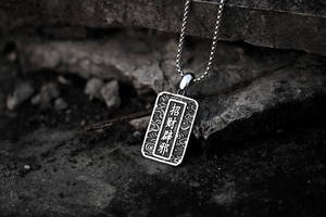 Macro detail of stainless steel rectangular pendant with traditional cloud patterns
