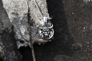Detail view of retro bull head stainless steel pendant on rugged concrete surface