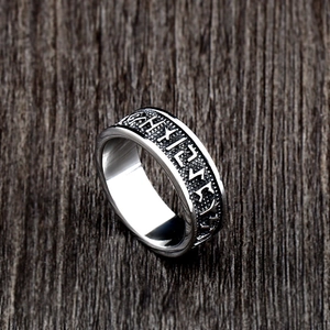 Macro shot of silver Viking rune ring featuring engraved stainless steel band on wood