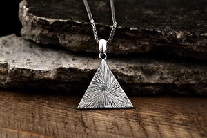 Macro shot of silver stainless steel Eye of Egypt triangle pendant with wheat chain