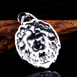 Close-up of vintage stainless steel lion head pendant with embossed details on wood branch