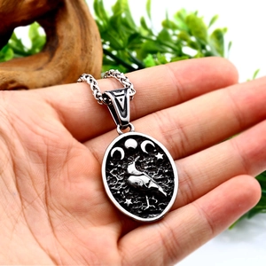 Gravure détaillée d'un corbeau viking et croissant de lune sur un pendentif ovale en acier