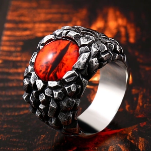Macro shot of gothic stainless steel ring with red dragon eye gemstone and scale texture